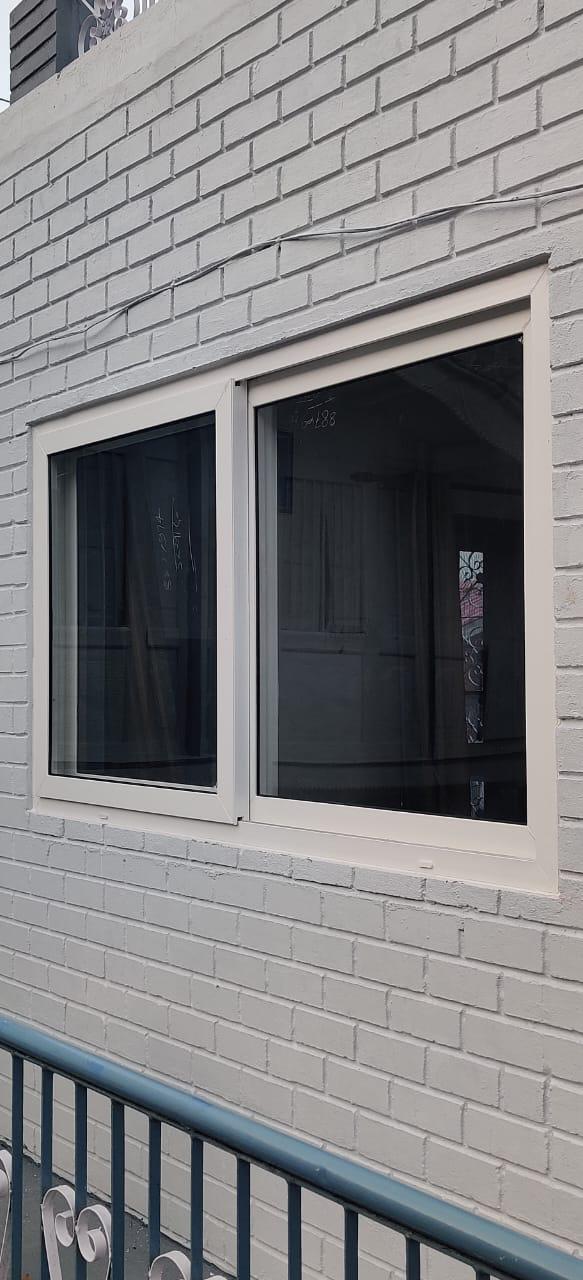White framed sliding window fitted in a painted brick wall